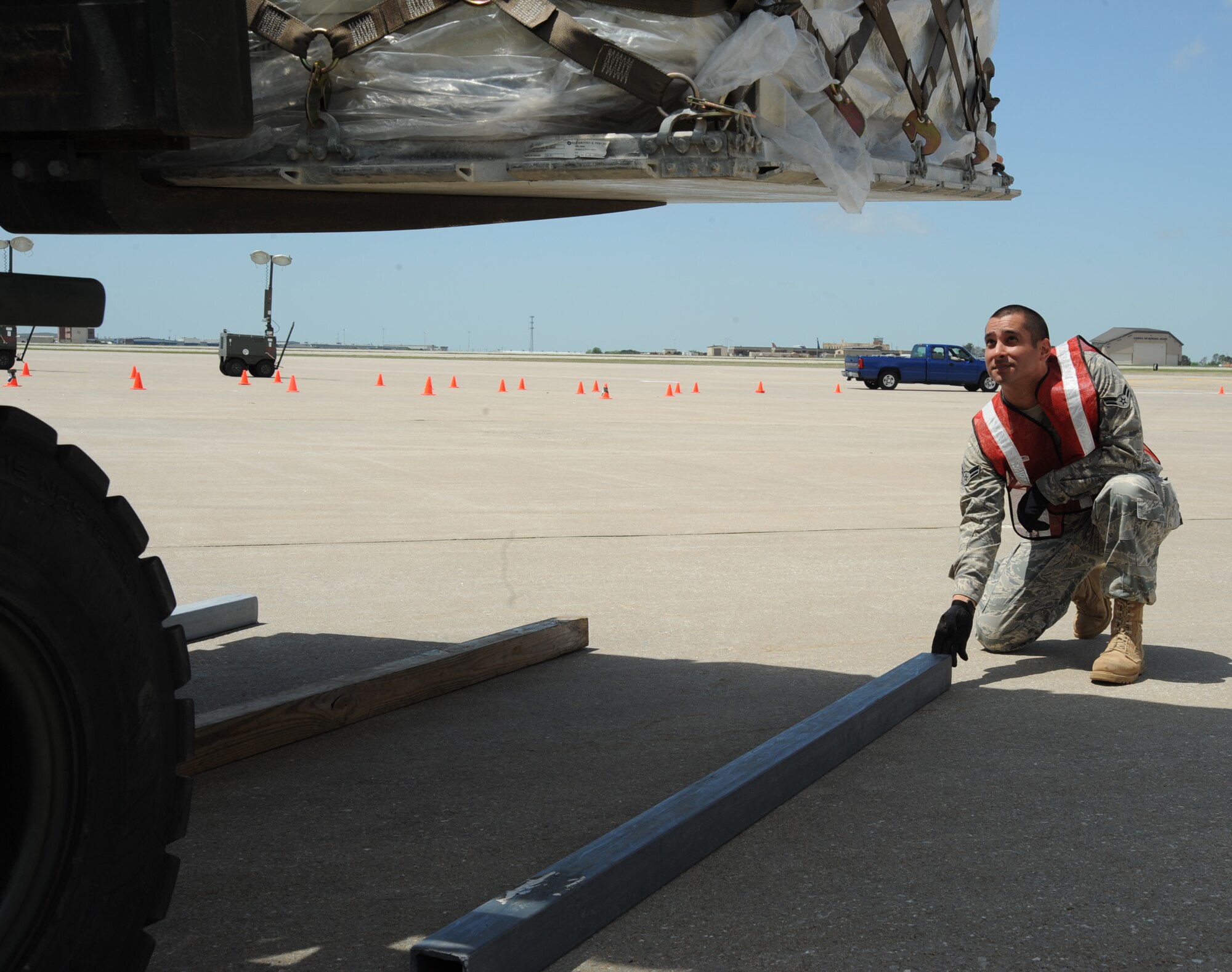 MCCONNELL AIR FORCE BASE, Kan. -- Airman 1st Class David Ferreiera, 22nd Logistics Readiness Squadron, places a third piece of dunnage on the ground as a cargo pallet is lowered down on the flight line during an operational readiness exercise, May 6. In the distance, flight line safety watches from a truck as Airmen load and unload pallets. (Photo by Senior Airman Laura Suttles)