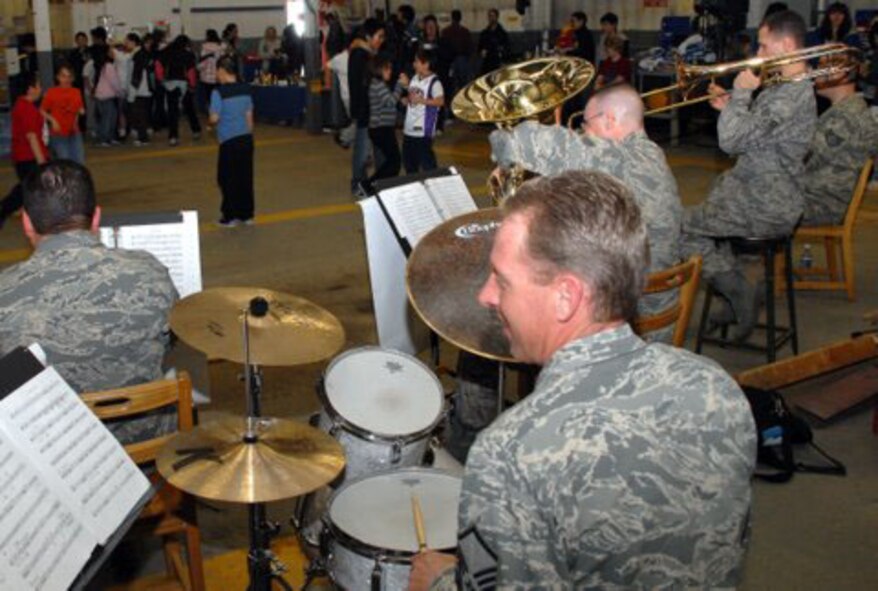 Master Sgt. Scott Weller, percussionist for the Air Force Band of the Pacific's Alaska Brass section, smiles while Kaktovik children dance in the background. The Alaska Brass Section, from Elmendorf Air Force Base, Alaska, traveled to Kaktovik April 27 to help host an open house at the Barter Island Radar Site. (U.S. Air Force photo/1st Lt. John Callahan)