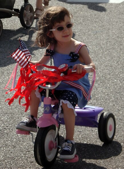 Isabel Allori cruises along during Vance’s Child Development Center’s Red, White & Blue Parade on base April 24, honoring the Month of the Military Child. (Photo by Melissa Seror)