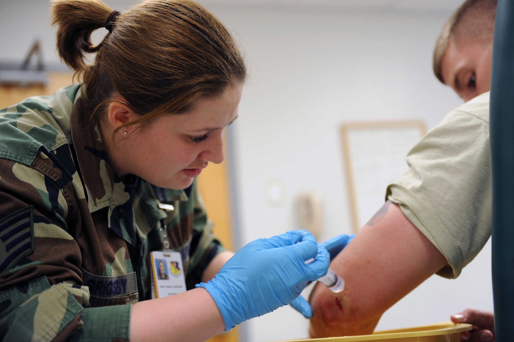 WHITEMAN AIR FORCE BASE, Mo. -- Staff Sgt. Angela Grigsby, 509th Medical Operations Squadron, cleans out a wound on the elbow of  Airman 1st Classs Philip Casali, 509th Munitions Squadron, before he receives stitches for an accident that happened at his shop April 22..  (U.S. Air Force photo/ Senior Airman Jason Huddleston)