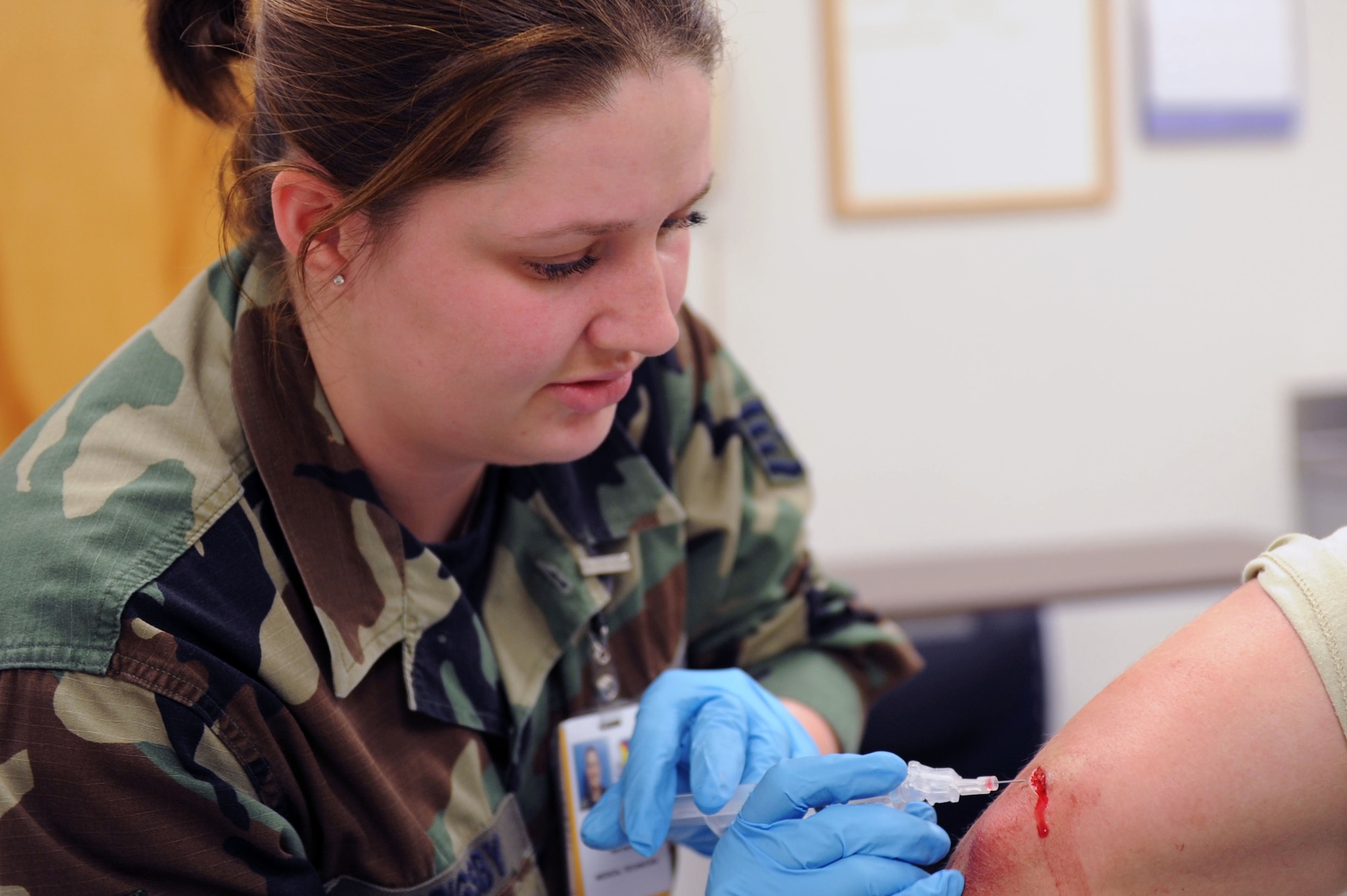 WHITEMAN AIR FORCE BASE, Mo. -- Staff Sgt. Angela Grigsby, 509th Medical Operations Squadron, gives a shot to numb up the elbow of  Airman 1st Classs Philip Casali, 509th Munitions Squadron, before he receives stitches for an accident that happened at his shop April 22..  (U.S. Air Force photo/ Senior Airman Jason Huddleston)
