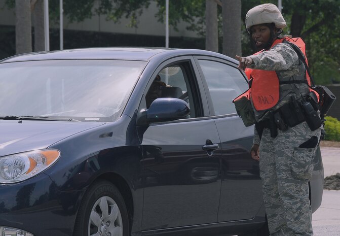 Staff Sgt. Loletha Brooks directs a driver to perform a U-turn in front of wing headquarters here and to proceed away from a cordoned area May 4. Sergeant Brooks swiftly posted on the scene putting training into action in response to a suspicious package just minutes after the end of an emergency management base exercise. Sergeant Brooks serves as a patrolman with the 437th Security Forces Squadron. (U.S. Air Force photo/Staff Sgt. Daniel Bowles)
