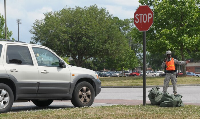 Senior Airman Brandon Hall directs a driver onto Hill Boulevard in front of wing headquarters here, keeping a cordoned area clear May 4. Airman Hall arrived at the intersection of Gates Avenue and Hill Boulevard putting his training into action in response to a real-world contingency operation involving a suspicious package. Airman Hall serves as a patrolman with the 437th Security Forces Squadron. (U.S. Air Force photo/Staff Sgt. Daniel Bowles)