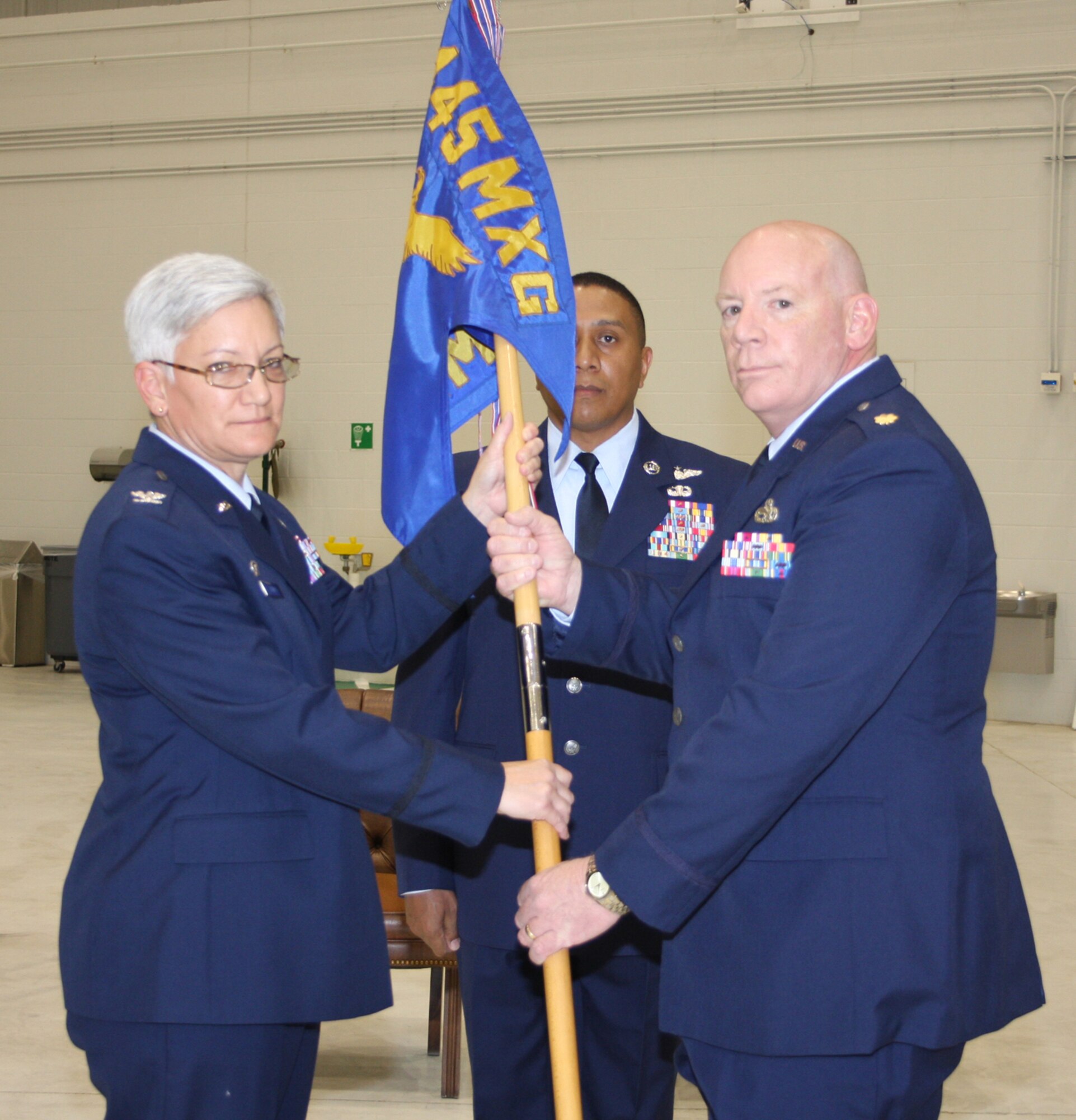 WRIGHT-PATTERSON AFB, Ohio – Col. Anna Schulte, 445th Maintenance Group commander, passes the guidon to Maj. George Palmer, incoming Aircraft Maintenance Squadron commander, during the May 3 Assumption of Command ceremony. Senior Master Sgt. James Felton, Jr., AMXS first sergeant, looks on.  Maj. Palmer was the aircraft maintenance commander for the 459th Air Refueling Wing at Andrews Air Force Base, Md., prior to coming to the wing.  (Air Force photo/Staff Sgt. Ken LaRock)