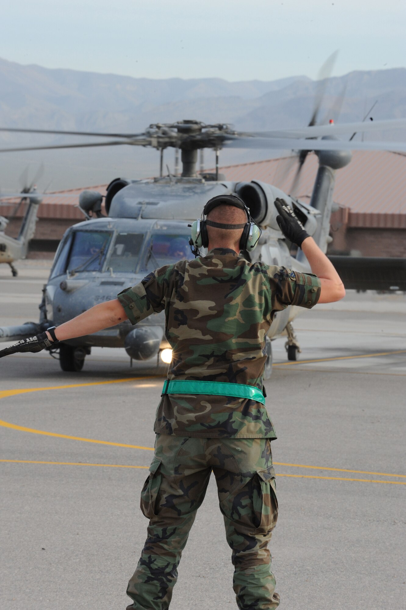 Airman 1st Class Christopher Mallaire prepares to marshall out an HH-60G Pave Hawk departing for a rescue mission May 1 at Nellis Air Force Base, Nev. Four helicopters and 24 Airmen from the 58th and 66th Rescue Squadrons deployed to assist in the search for a pilot and passenger who were aboard a motorized sailplane that disappeared from radar April 24 in the Sierra Nevada Mountain Range near Mammoth Lakes, Calif. Airman Mallaire is a crew chief with the 763rd Aircraft Maintenance Squadron. (U.S. Air Force photo/Senior Airman Nadine Y. Barclay)
