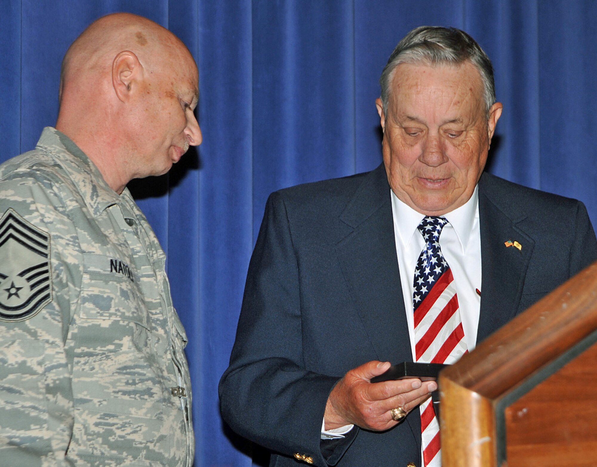 Retired Major Kenneth Carpenter receives a decorative coaster from Chief Master Sgt. David Natoli, 721st Mission Support Group superintendent, following his Year of Leadership speech at the base auditorium April 27. The blue and silver coasters, which are made of glass and metal, are given to visiting distinguished visitors as a token of appreciation for their support of Peterson Airmen and the United Stated Air Force. (Air Force photo by Dennis Howk)

