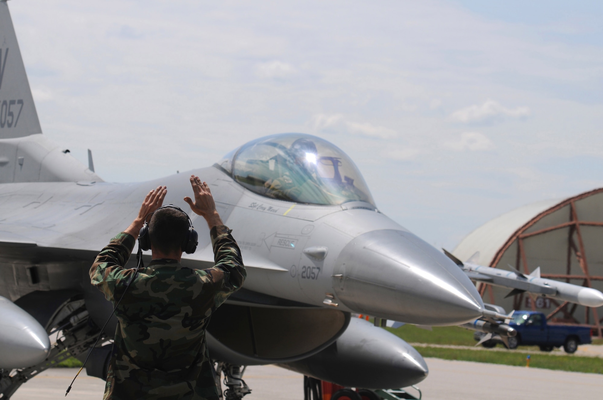 Airman 1st Class Richard Sprott, 31st Aircraft Maintenance Squadron crew chief, marshalls F-16 tail number 2057 down the runway before a routine training mission on May 5, 2009. This particular flight pushed the jet past its 7,000 flying hour-mark, which is a first in the Aviano F-16 Fighting Falcon fleet. (U.S. Air Force photo/Staff Sgt. Patrick Dixon)
