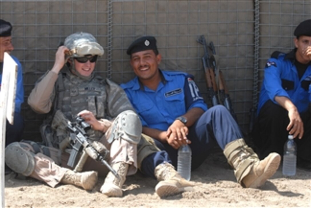 U.S. Air Force Senior Airman Miller, attached to the Rough Riders, 91st Battalion, Task Force Dragon, relaxes with a group of Iraqi policemen at a firing range in Mahmudiyah, Iraq, on April 23, 2009.  The Rough Riders are instructing Iraqi policemen how to safely aim and fire their weapons.  These policemen will be sent out to instruct other Iraqi police officers throughout the country.  