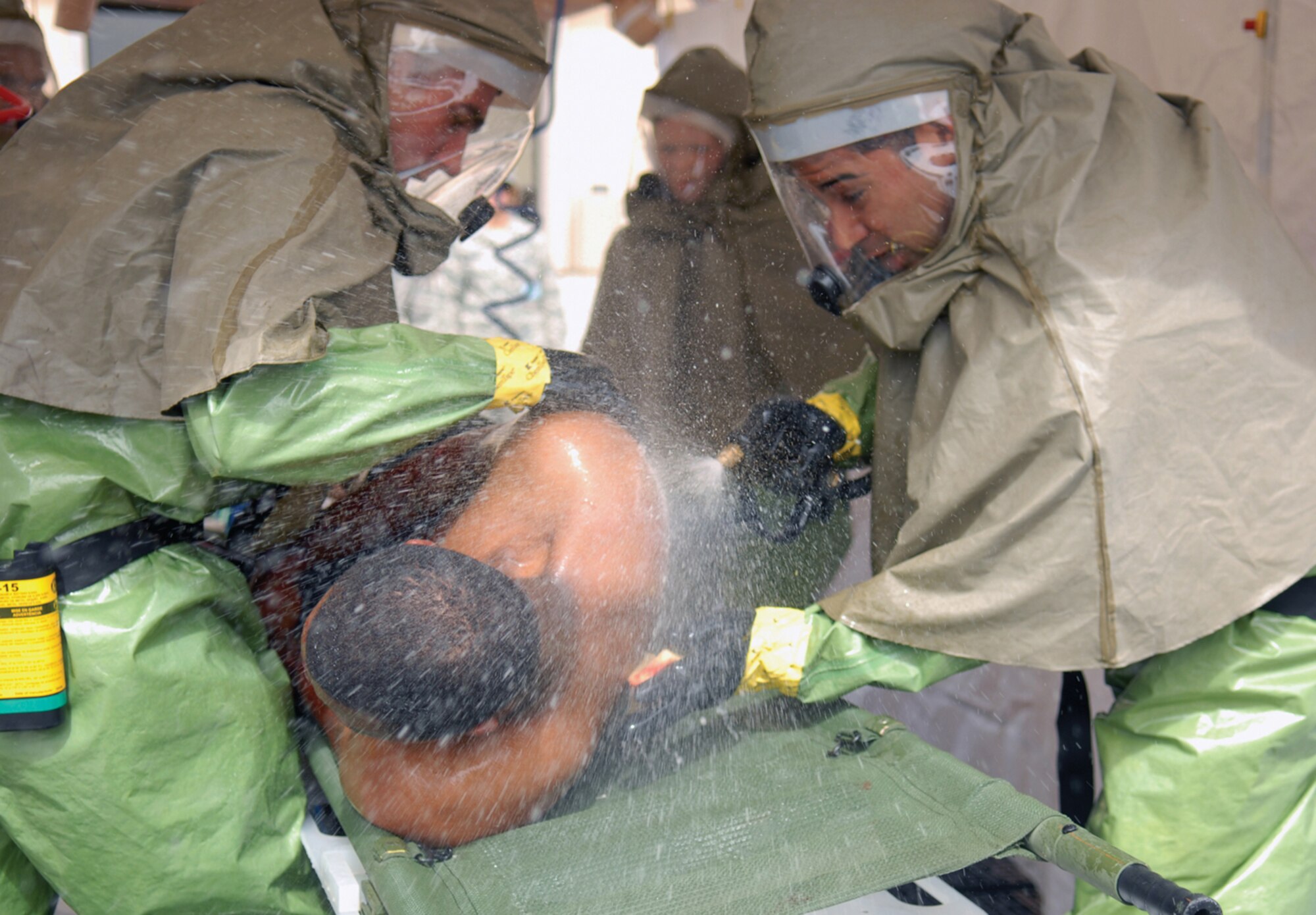 Staff Sgt. Rolando Guerrero, 56th Medical Operations Squadron physical medicine technician, and Airman 1st Class Tyler Travis, 56th Medical Operations Squadron, decontaminate Airman 1st Class Daniel Evans, 56th Force Support Squadron, in the decontamination tent during a major accident response exercise Tuesday. (U.S. Air Force photo/Airman 1st Class Sandra Welch.)