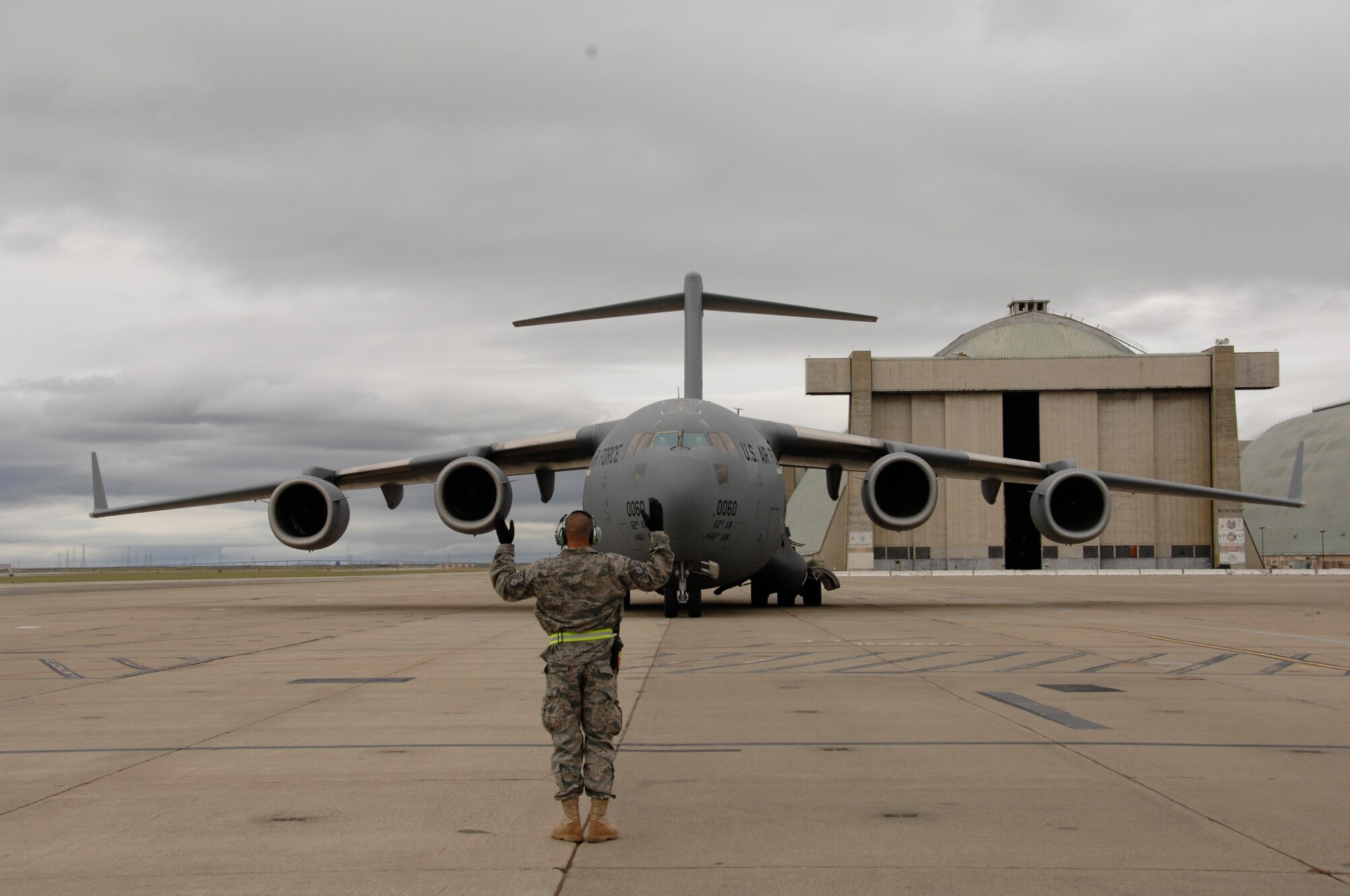 Tech Sgt. Fernando Wilkins, a 129th Maintenance Group crew chief, directs an incoming C-17 Globemaster to its parking spot at Moffett Federal Airfield, Calif.  The C-17 and its crews from McChord Air Force Base, Wash., arrived at Moffett to pick up passengers and equipment deploying to Afghanistan, May 3, 2009. (U.S. Air Force photo by Staff Sgt. Kim E. Ramirez)