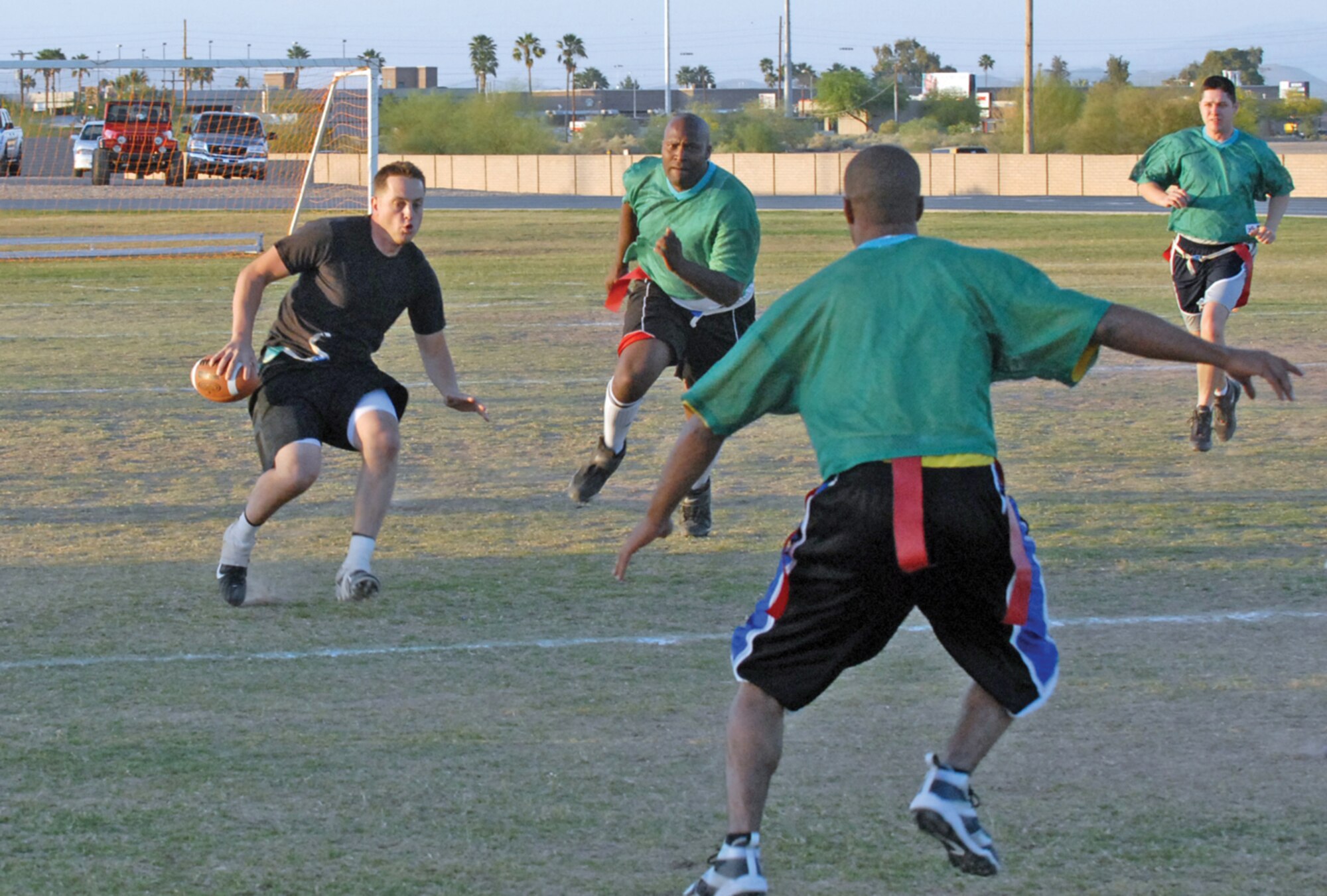 Richard Janzer, 56th Civil Engineer Squadron quarterback, tries to escape incoming defenders from the 61st Aircraft Maintenance Unit, during the 56th Force Support Squadron Fitness Center intramural flag football championship April 30. The 61st AMU defeated CE, the two-time flag football champions, during overtime 27-21. (U.S. Air Force photo/ Senior Airman C.J. Hatch)