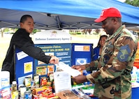 From left to right, Rommel Castro and Josie Sabater, Sales Store Checkers with the Defense Commissary Agency, give Chief Tyrone Matthews a list of items that should be included in an emergency survival kit in the event of an unexpected disaster during Airman Preparedness Day May 1, 2009 at Travis Air Force Base, California. (U.S. Air Force photo by Civ/Amanda Lopez)