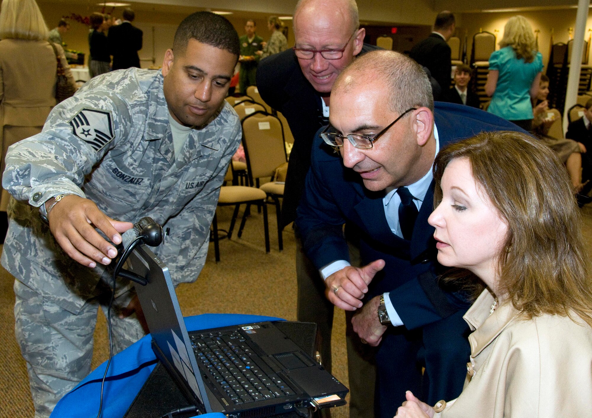 Master Sgt. Rafael Gonzalez, left, 403rd Wing client support administrator, assists Brig. Gen. James Muscatell, 403rd Wing commander, and his wife Nancy with a video teleconference so their son, Marine Cpl. Todd Lawson, could attend the general’s May 2 promotion ceremony while deployed to Southwest Asia.  In the background is family friend Fred Fletemeyer, honorary commander of the 302nd Airlift Wing, Colorado Springs, Colo.  (U.S. Air Force photo by Tech. Sgt. Ryan Labadens)
