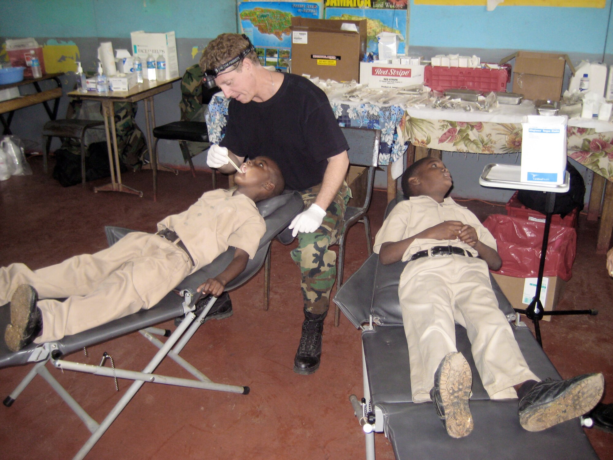 Lt. Col. (Dr.) Mark Emshwiller inspects the teeth of two Jamaican school children to identify cavities and offer referrals April 15 in Jamaica. While at Lottery All Age School, Colonel Emshwiller saw 108 children in two hours. Colonel Emshwiller is an Arizona Air National Guard dentist. (U.S. Air Force photo/Maj. Christine Rhodes) 
