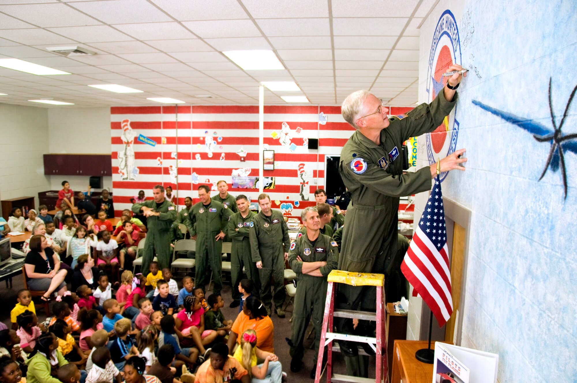 Lt. Col. Jon Talbot, chief weather reconnaissance officer, 53rd Weather Reconnaissance Squadron, signs his name on a wall size mural painted in the library at Pass Road Elementary, Gulfport, Miss. The mural was painted to express thanks for the services Citizen Airmen of the 403rd Wing provide. ?You guys are Hollywood to these kids, and we thought it would be a great idea if you could come sign it,? said Ms. Penny Walton, library media specialist, Pass Road Elementary. (U.S. Air Force Photo by 1st. Lt. J. Justin Pearce)
