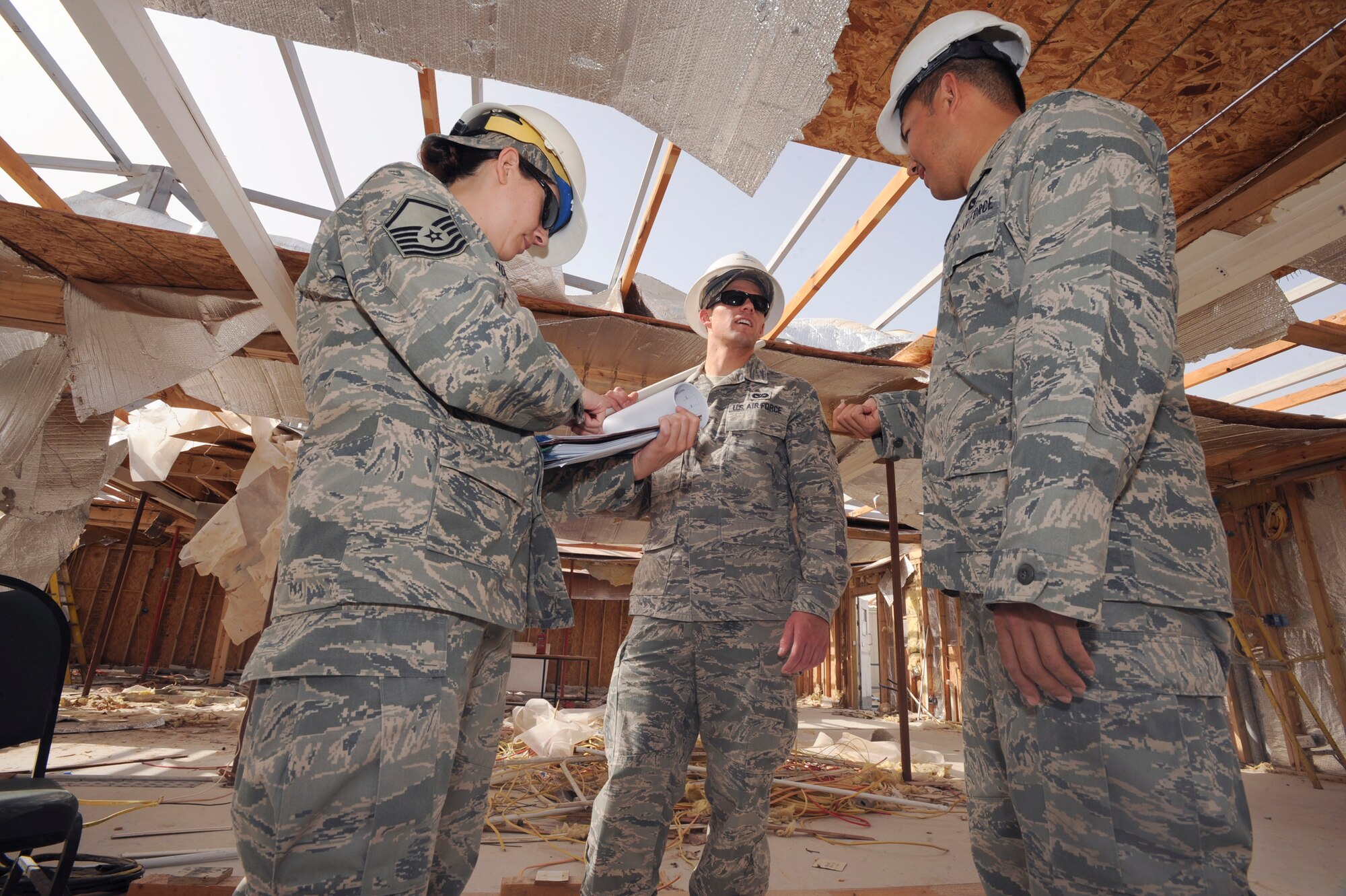 Master Sgt. Kelly Dodson, a contracting officer with the 379th Expeditionary Contracting Squadron, talks with Senior Airman Jake Duncan, the construction manager, and Captain Richard Wong, the project manager both with the 379th Expeditionary Civil Engineer Squadron, during demolition of the old Independence Dining Facility here, May 4, 2009, in an undisclosed location in Southwest Asia.  The Contracting Squadron and Civil Engineer Squadron, work hand in hand to ensure the contractors keep to the agreed upon schedule.  Sergeant Dodson is native to Phoenix, Ariz. and is deployed from the Arizona Air National Guard, while Senior Airman Jake Duncan hails from Monteca, Calif., and finally Capt. Wong is originally from Norcross, Ga. both are deployed from Travis Air Force Base, Calif., all three in support of Operations Iraqi and Enduring Freedom and Combined Joint Task Force - Horn of Africa.  (U.S. Air Force Photo by Staff Sgt. Joshua Garcia/released)