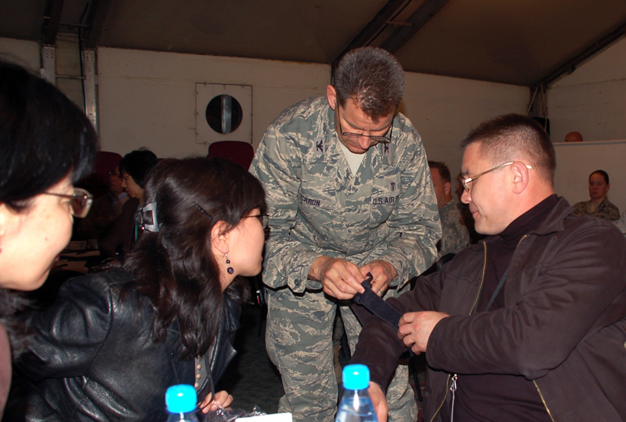 Col. (Dr.) Gerard Caron demonstrates the ease of a self-administering tourniquet during the 376th Expeditionary Medical Group's Coalition Medical Symposium held recently at Manas Air Base, Kyrgyzstan. Guests attending the symposium were from the Spanish coalition medical staff, U.S. Embassy medical unit, Peace Corps medical staff and the Bishkek Research Center of Trauma and Orthopedics. Colonel Caron is the 376th EMDG commander and is deployed from Randolph Air Force Base, Texas. (U.S. Air Force photo/Tech. Sgt. Phyllis Hanson) 