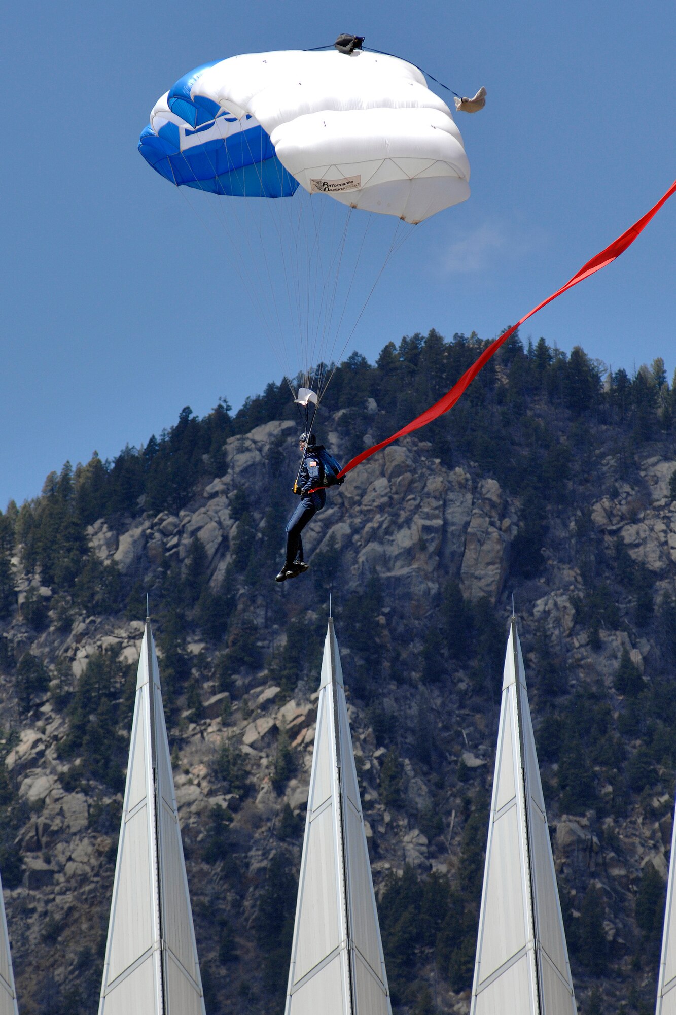 A member of the U.S. Air Force Academy's Wings of Blue Parachute team carefully maneuvers his canopy away from the spires of the Cadet Chapel toward a successful landing in the Academy's cadet area in Colorado May 6. The team performed a demonstration jump during the afternoon meal formation in front of the entire cadet wing and Academy visitors. (U.S. Air Force photo/Dennis Rogers)