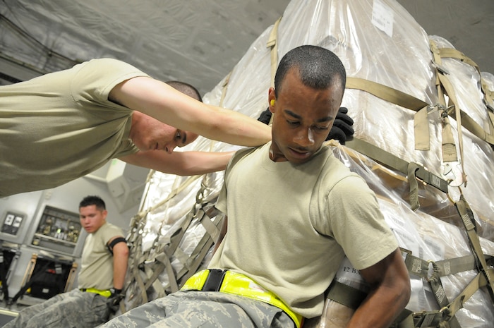 U.S. Air Force Airman 1st Class Marvin Richardson, front, Airman 1st Class Daniel Anderson, center, and Airman Rodrigo Maranon, back, push a pallet of personal protection kits onto a C-17 at Charleston Air Force Base, S.C., May 8, 2009. Thirty thousand personal protection kits were shipped to Haiti, El Salvador, Guatemala, Honduras and Nicaragua, where health-care officials are responding to confirmed and suspected cases of H1N1 Influenza-A infections. U.S. Southern Command, headquartered in Miami, directed the mission after learning health officials submitted requests for assistance to U.S. embassies in their respective countries. Airmen Richardson, Anderson and Maranon are air transportation specialists with 437th Aerial Port Squadron at Charleston AFB. (U.S. Air Force photo by James M. Bowman)(RELEASED)