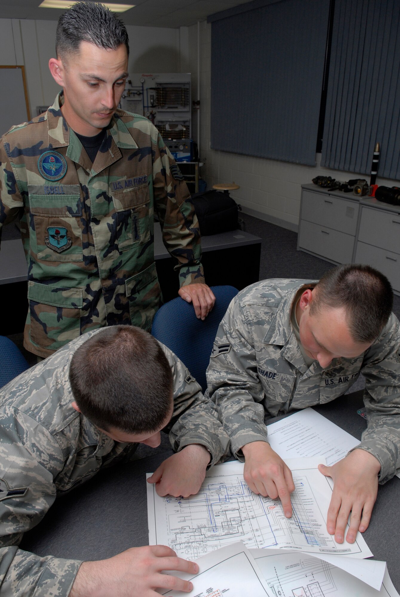 VANDENBERG AIR FORCE BASE, Calif. -- Keeping his students on track, Staff Sgt. Dustin Isbell, a 532nd Training Squadron missile and space systems facilities instructor, watches as Airman Ryan Turner and Airman 1st Class Adam Shade, 532nd TRS students, look over a power schematic here May 4. This course provides students the skills and knowledge needed to maintain and operate launch facility and missile alert facility diesel-electrical and electrical power systems, support vehicles, refrigeration and environmental control systems, and waste disposal systems.  It covers fundamentals of electrical circuits, symbols, components, wiring diagrams, microprocessors and monitors, as well as diesel electrical units. Sergeant Isbell has been an instructor for a year. (U.S. Air Force photo/Senior Airman Christian Thomas)
