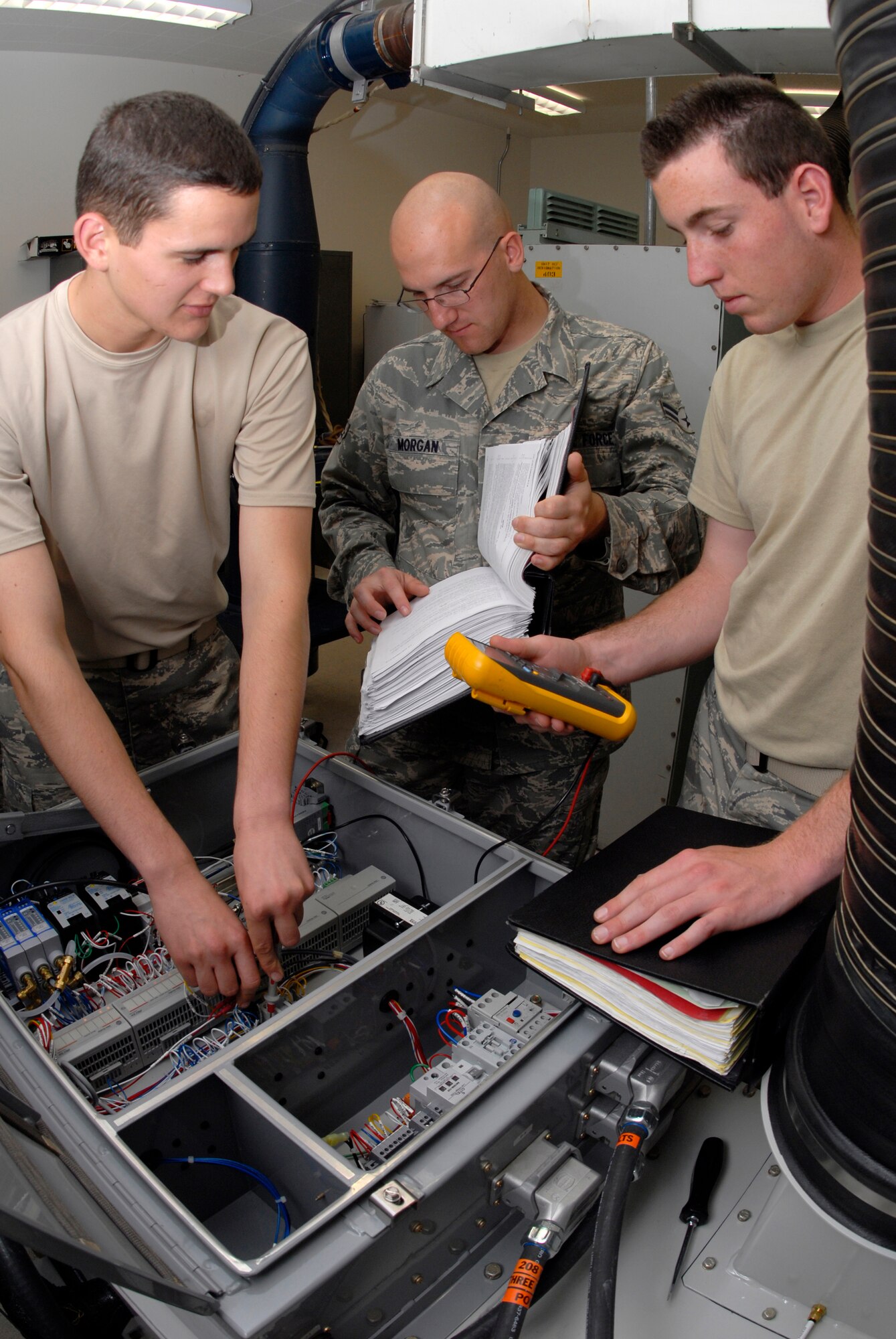 VANDENBERG AIR FORCE BASE, Calif. -- Working as a team, Airman Patrick Cosby, Airman 1st Class Jerad Morgan, and Airman 1st Class Jeff Estes, 532nd Training Squadron students, troubleshoot a new environmental control system for the missile facilities here May 5. The missile and space systems facilities course provides students the skills and knowledge needed to maintain and operate launch facility and missile alert facility diesel-electrical and electrical power systems, support vehicles, refrigeration and environmental control systems, and waste disposal systems. (U.S. Air Force photo/Senior Airman Christian Thomas)