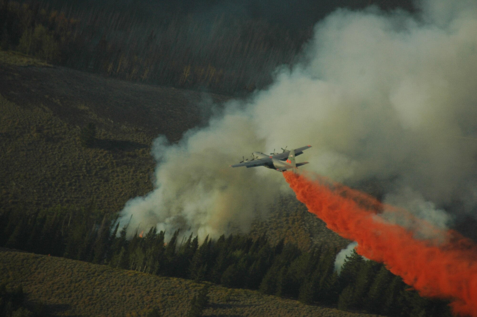 A C-130 uses aerial firefighting equipment known as the Modular Airborne Fire Fighting System to drop red-colored retardant, or ‘slurry’ as it is sometimes called, from the plane into the air over a fire. MAFFS was established by Congress in the early 1970s to create a national response system to better fight major fires. (U.S. Air Force Photo)