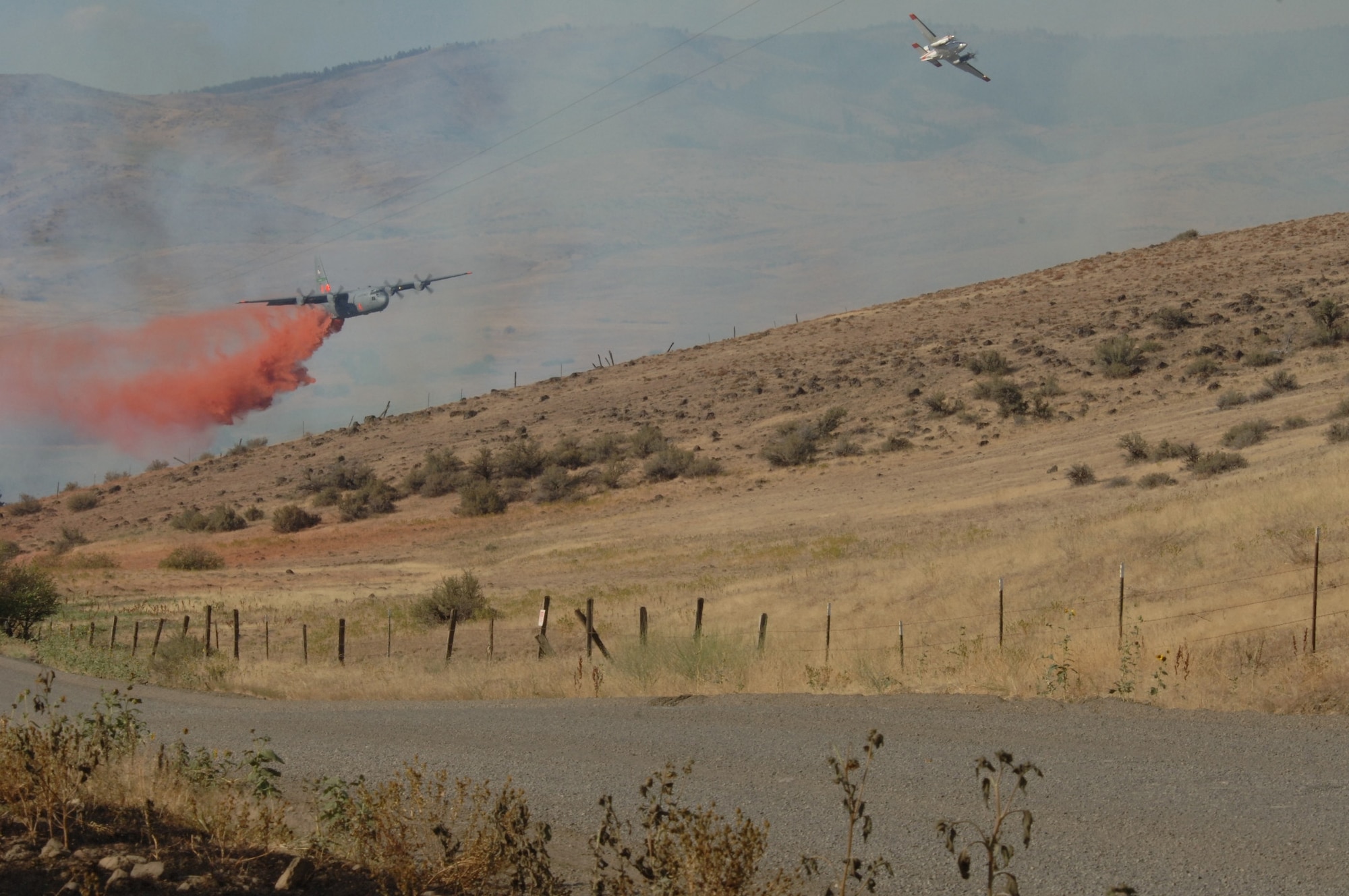 A C-130 uses aerial firefighting equipment known as the Modular Airborne Fire Fighting System to drop red-colored retardant, or ‘slurry’ as it is sometimes called, from the plane into the air over a fire. MAFFS was established by Congress in the early 1970s to create a national response system to better fight major fires. (U.S. Air Force Photo)