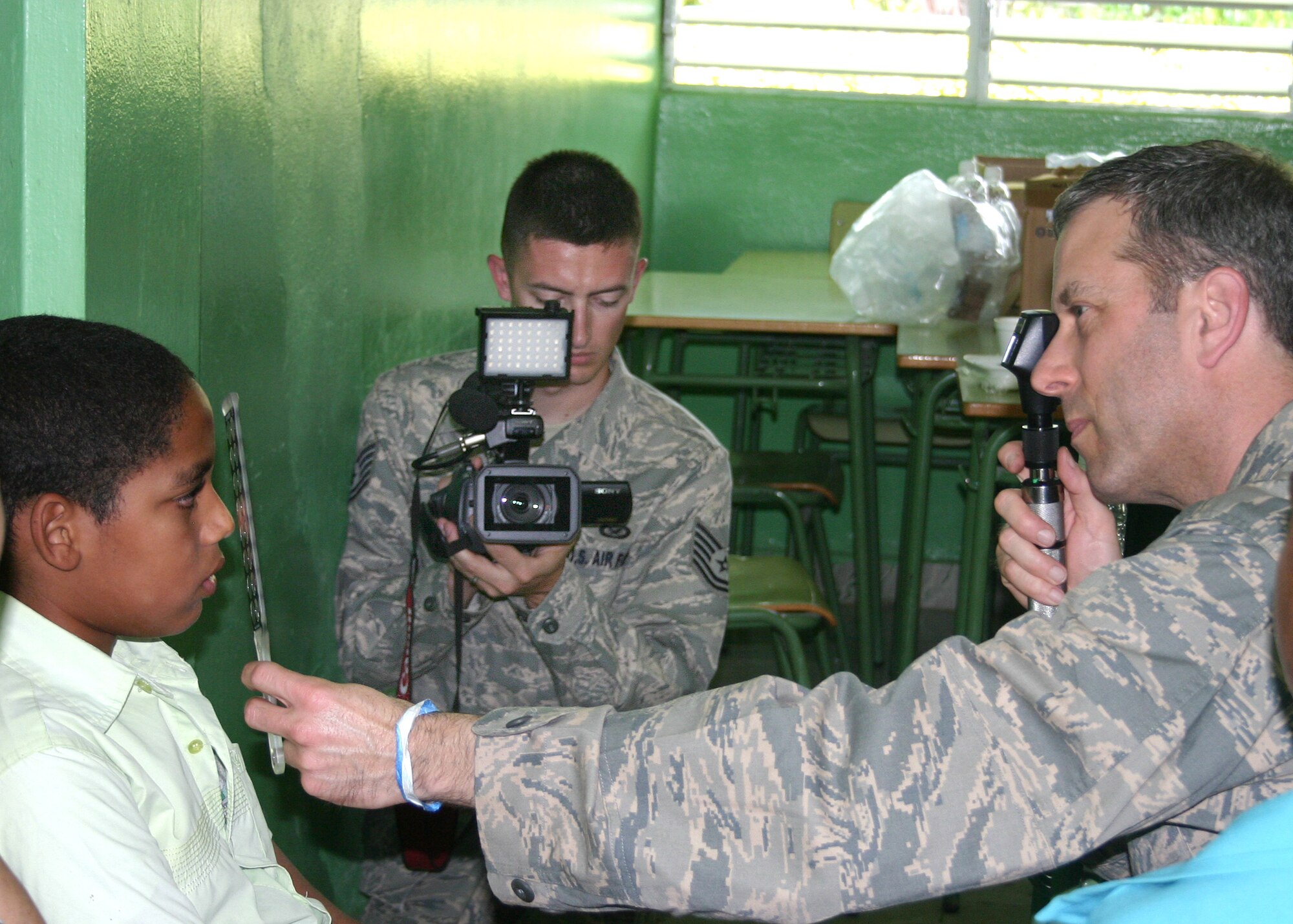 Tech. Sgt. Ken Raimondi videotapes Lt. Col. Christopher Rugaber performing an exam on a young boy in Padre de Las Casas, Dominican Republic. Colonel Rugaber is an optometrist assigned to the 910th Medical Squadron at Youngstown Air Reserve Station, Ohio. Sergeant Raimondi is the noncommissioned officer in charge of Air Force Recruiting Service Broadcast Operations. (U.S. Air Force photo/Dale Eckroth)