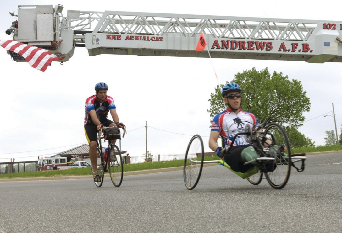 Wounded warriors exit Andrews through the North Gate under a U.S. flag draped from the bucket of a fire truck. For many, the Soldier Ride provides an important step in their interaction in the community and doing things they never thought they could again. (U.S. Air Force photo/ Senior Airman Renae Kleckner)