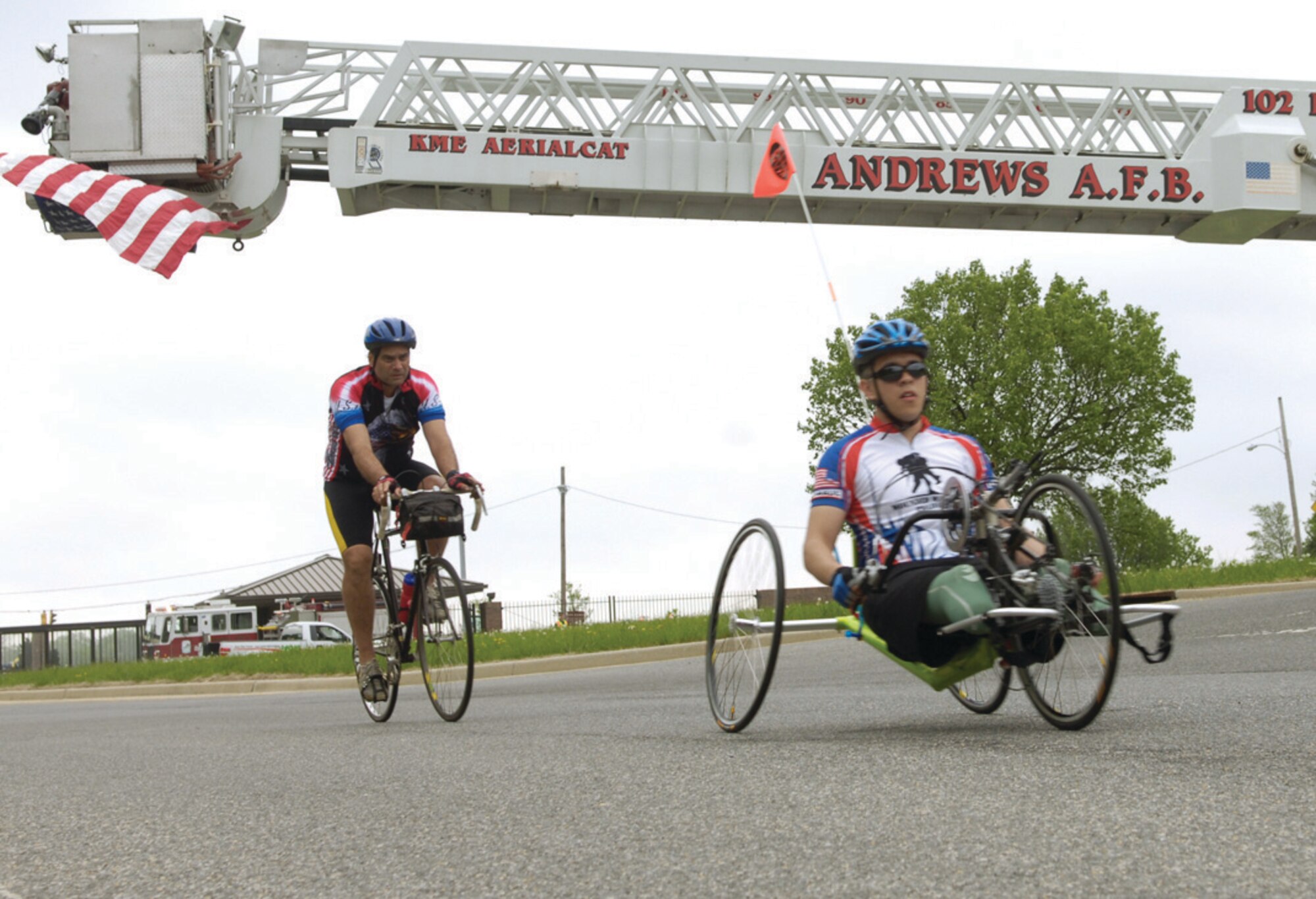 Wounded warriors exit Andrews through the North Gate under a U.S. flag draped from the bucket of a fire truck. For many, the Soldier Ride provides an important step in their interaction in the community and doing things they never thought they could again. (U.S. Air Force photo/ Senior Airman Renae Kleckner)