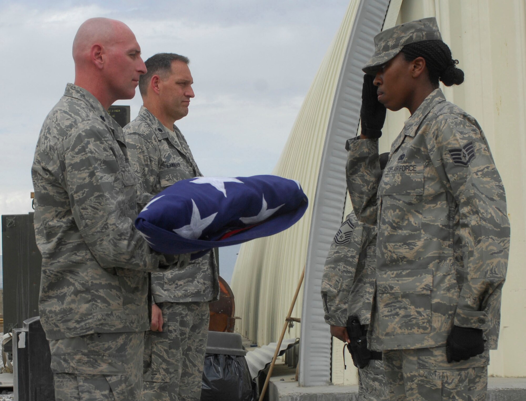 Lt. Col. Brett Nelson, 23rd Special Tactics Squadron commander, receives a flag from Staff Sgt. Theresa Wilson, Supply Technician, 1st Expeditionary Special Operations Maintenance Squadron, at Bagram Air Field, Afghanistan, May 1. The flag was lowered during a building dedication ceremony for Staff Sgt. Casey Crate, a combat controller who was killed on May 30, 2005, in central Iraq. The flag was folded by members of the 1st Special Operations Maintenance Squadron.  The flag will be flown back to the United States and given to Sergeant Crate's mother. (U.S. Air Force photo/ Senior Airman Erik Cardenas)(Released)
