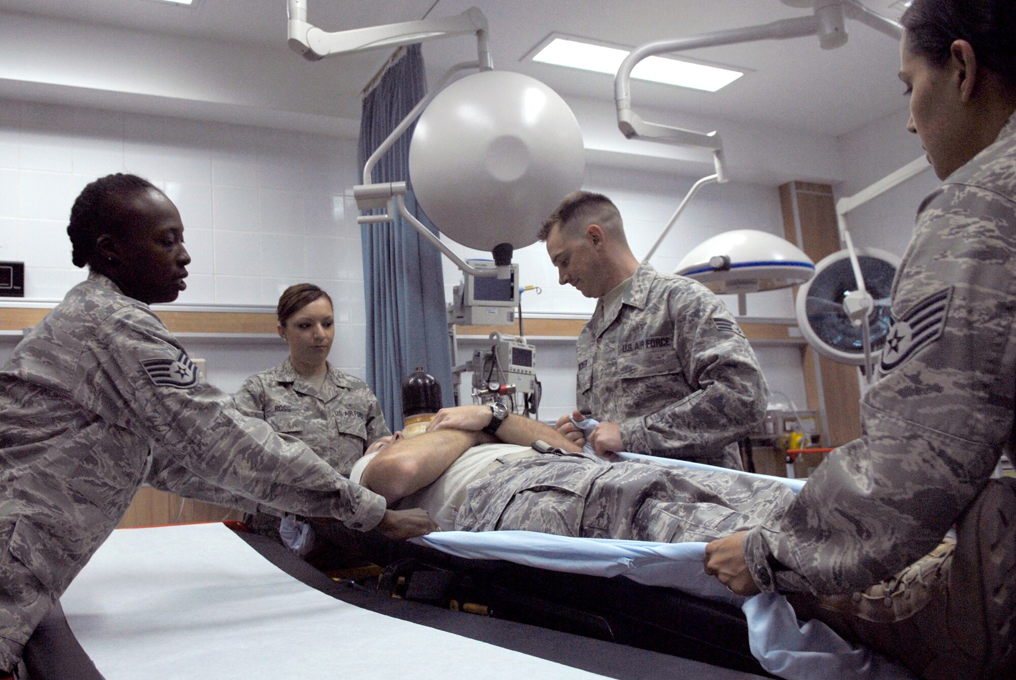 Medical Technicians of the 379th Expeditionary Medical Group practice moving a patient off a gurney in the emergency room, May 6, 2009, at an undisclosed location.  The med techs are first responders who provide basic medical care for patients by checking vitals and performing an initial assessment of their patients.  All of the med techs are deployed here in support of Operations Iraqi and Enduring Freedom and Combined Joint Task Force - Horn of Africa.  (U.S. Air Force photo/Senior Airman Andrew Satran/released)