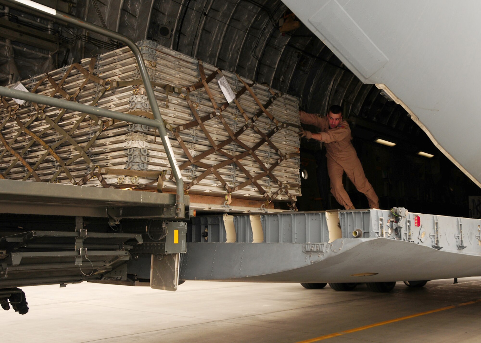 SOUTHWEST ASIA -- Staff Sgt. Dan Carlisle, 816th Expeditionary Airlift Squadron, pushes a pallet onto a 60K aircraft cargo loader during an off-load at an air base in Southwest Asia, May 6. A C-17 Globemaster can carry up to 170,900 pounds of cargo distributed at max over 18 standardized pallets or a mix of palletized cargo and vehicles. Sergeant Carlisle is currently deployed from Dover Air Force Base, Del. and is originally from Aberdeen, Wash. (U.S. Air Force photo/ Senior Airman Courtney Richardson)