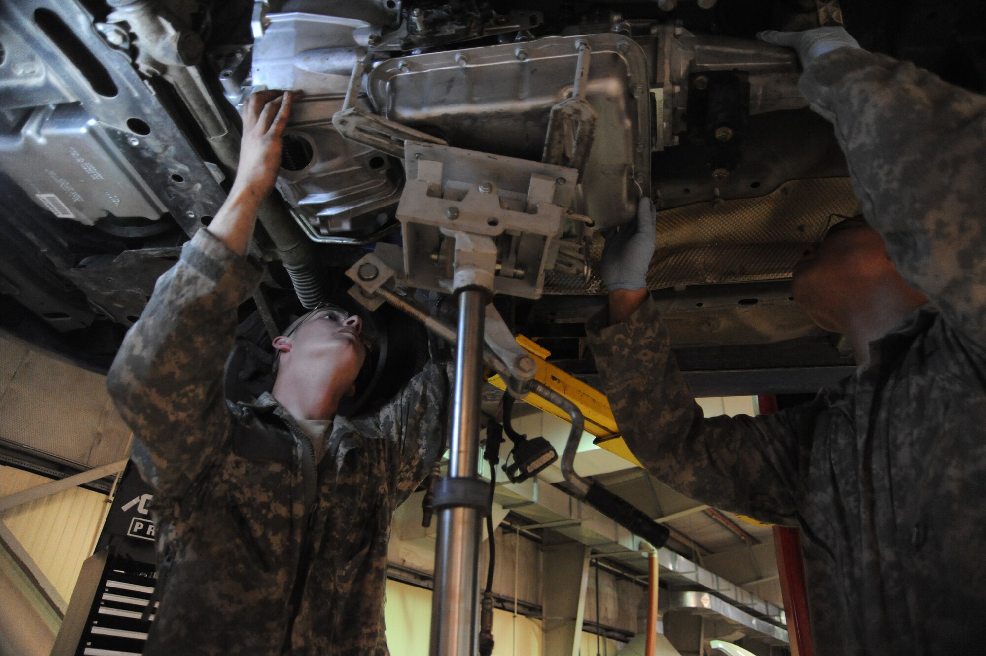 Senior Airman Adam Owens and Senior Airman Michael Jakubec, 380th Expeditionary Logistics Readiness Squadron, vehicle maintenance, raise up a new transmission into a Pontiac GTO, April 26 at an undisclosed location in Southwest Asia. The GTO is used as a chase car to help guide the U-2 Dragon Lady pilots during take-offs and landings. Airman Owens is deployed from 174th Air National Guard Base, Hancock Field, N.Y. and hails from Binghamton, N.Y. Airman Jakubec is deployed from Kadena AB, Japan and hails from Spanaway Wash.  (U.S. Air Force photo by Senior Airman Brian J. Ellis) (Released)