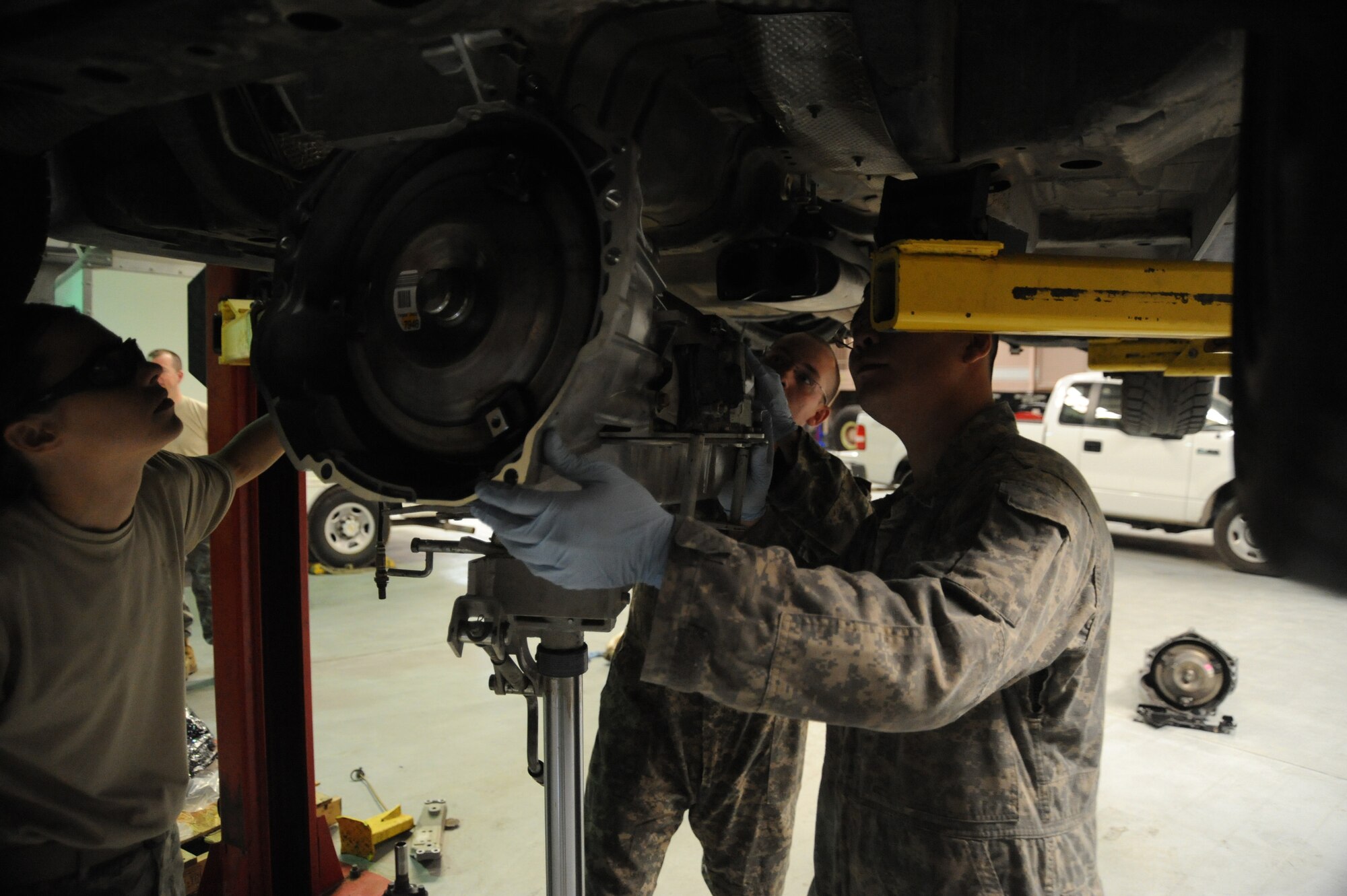 Lt. Col. Tanya Kubinec, 380th Expeditionary Logistics Readiness Squadron, commander, Senior Airman Adam Owens and Senior Airman Michael Jakubec, 380th ELRS, vehicle maintenance, line up a new transmission with the engine of a Pontiac GTO, April 26 at an undisclosed location in Southwest Asia. Colonel Kubinec coined the two Airmen for their work on the GTO as well as other critical vehicles belonging to the 380th Air Expeditionary Wing. Airman Owens is deployed from 174th Air National Guard Base, Hancock Field, N.Y. and hails from Binghamton, N.Y. Airman Jakubec is deployed from Kadena AB, Japan and hails from Spanaway Wash.  (U.S. Air Force photo by Senior Airman Brian J. Ellis) (Released)