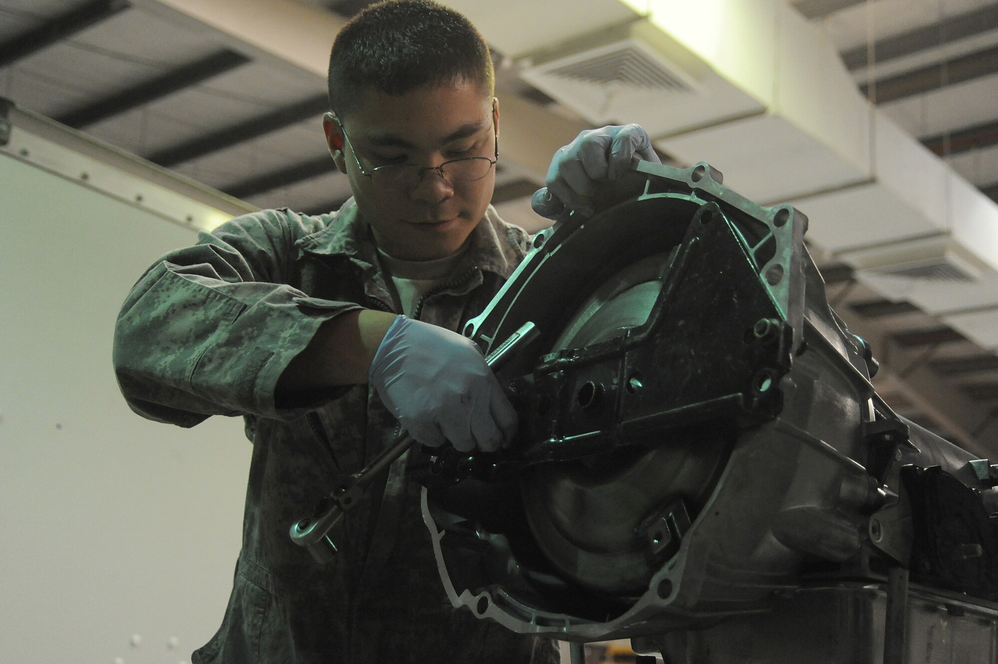 Senior Airman Michael Jakubec, 380th Expeditionary Logistics Readiness Squadron, vehicle maintenance, takes off a torque converter shield from a transmission, April 26 at an undisclosed location in Southwest Asia. The shield is placed on the transmission to protect the torque converter during shipping. Airman Jakubec is deployed from Kadena AB, Japan and hails from Spanaway Wash.  (U.S. Air Force photo by Senior Airman Brian J. Ellis) (Released)