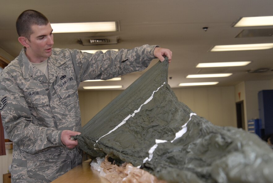 Staff Sgt Justin Slater, an aircrew flight equipment technician assigned to the 8th Operations Support Squadron, checks a parachute for rips and frays at Kunsan Air Base, Republic of Korea. Aircrew flight technicians are responsible for all of the equipment that will save a pilots life in the event the pilot has to eject from the aircraft. (U.S. Air Force Photo by Staff Sgt Jason Colbert)
