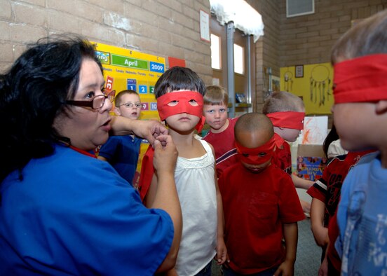 Mrs. Ruby Rodriguez, Child Development Center teacher, pins on "Superhero" capes for the annual Military Child Parade at Holloman Air Force Base, N.M., April 30. Each CDC age group from designed its own unique theme to display during the parade. (U.S. Airman 1st Class Veronica Stamps) 