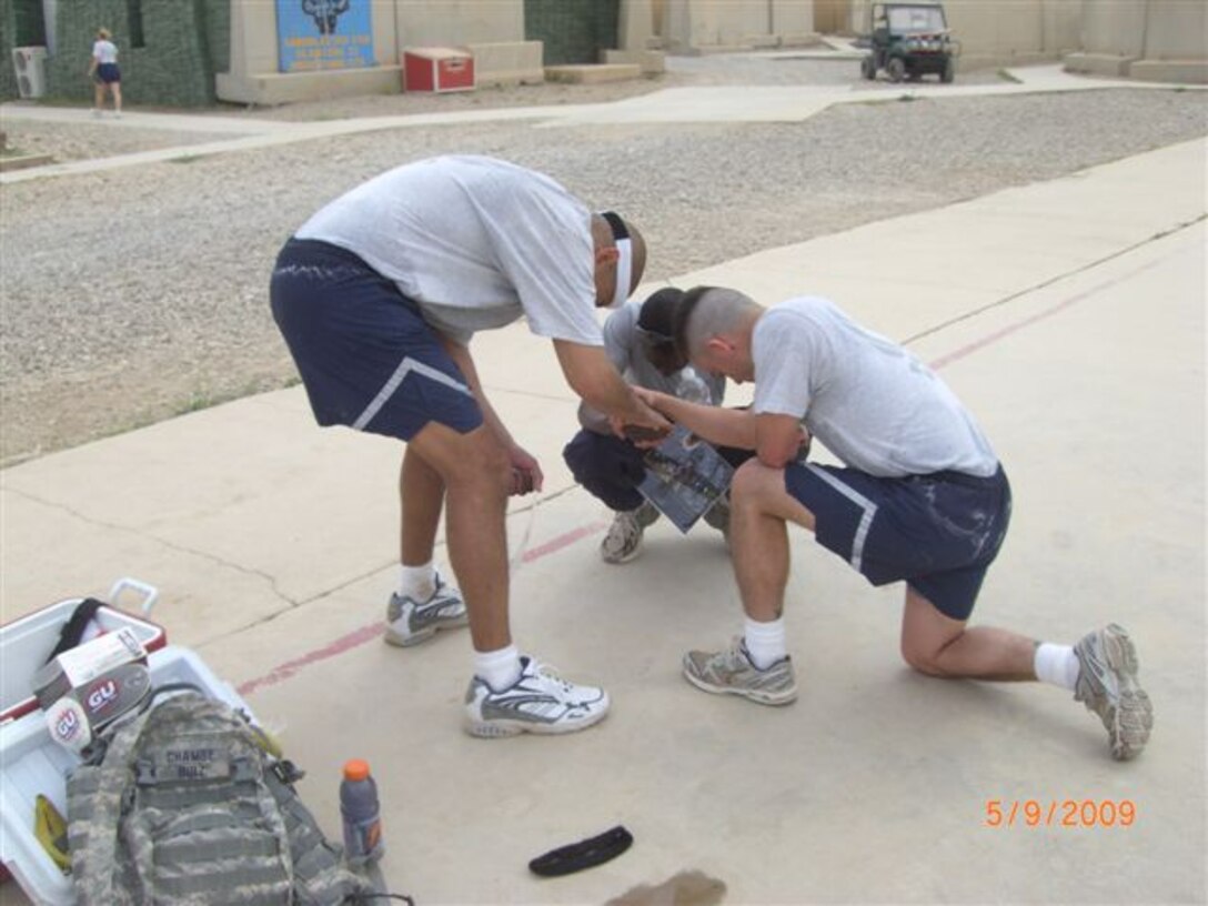 Staff Sgt. Sonny Hernandez, of the 445th Security Forces Squadron (standing), Kavuma Richard, a contractor from Uganda, Africa (in back) and Tech. Sgt. Sam A. Ruiz, of the 119th Wing Security Forces Squadron (kneeling), pray together after crossing the finish line.  The trio completed the Fargo Marathon from Iraq on May 9th.  