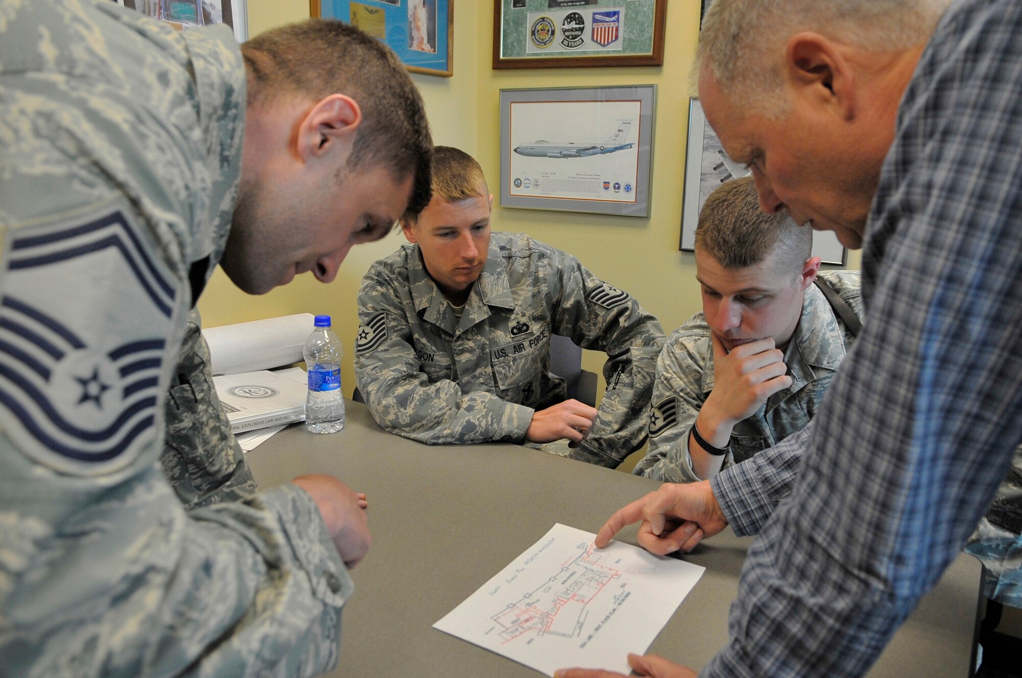 Senior Master Sgt. Albert Schneider, Tech. Sgt. Robert Wilson, Staff Sgt. Robert Brown and Kim Ellard look at a map of the new wing at the Fairbanks International Airport May 5. Teams from Eielson Air Force Base?s Security Forces Squadron and the explosive ordnance disposal flight assisted the Department of Homeland Security to clear the new wing of threats. Sergeant Schneider is assigned to the 354th Civil Engineer Squadron EOD flight, Sergeants Wilson and Brown are assigned to the 354th SFS, and Mr. Ellard is assigned to the DHS. (U.S. Air Force photo/Staff Sgt. Christopher Boitz)