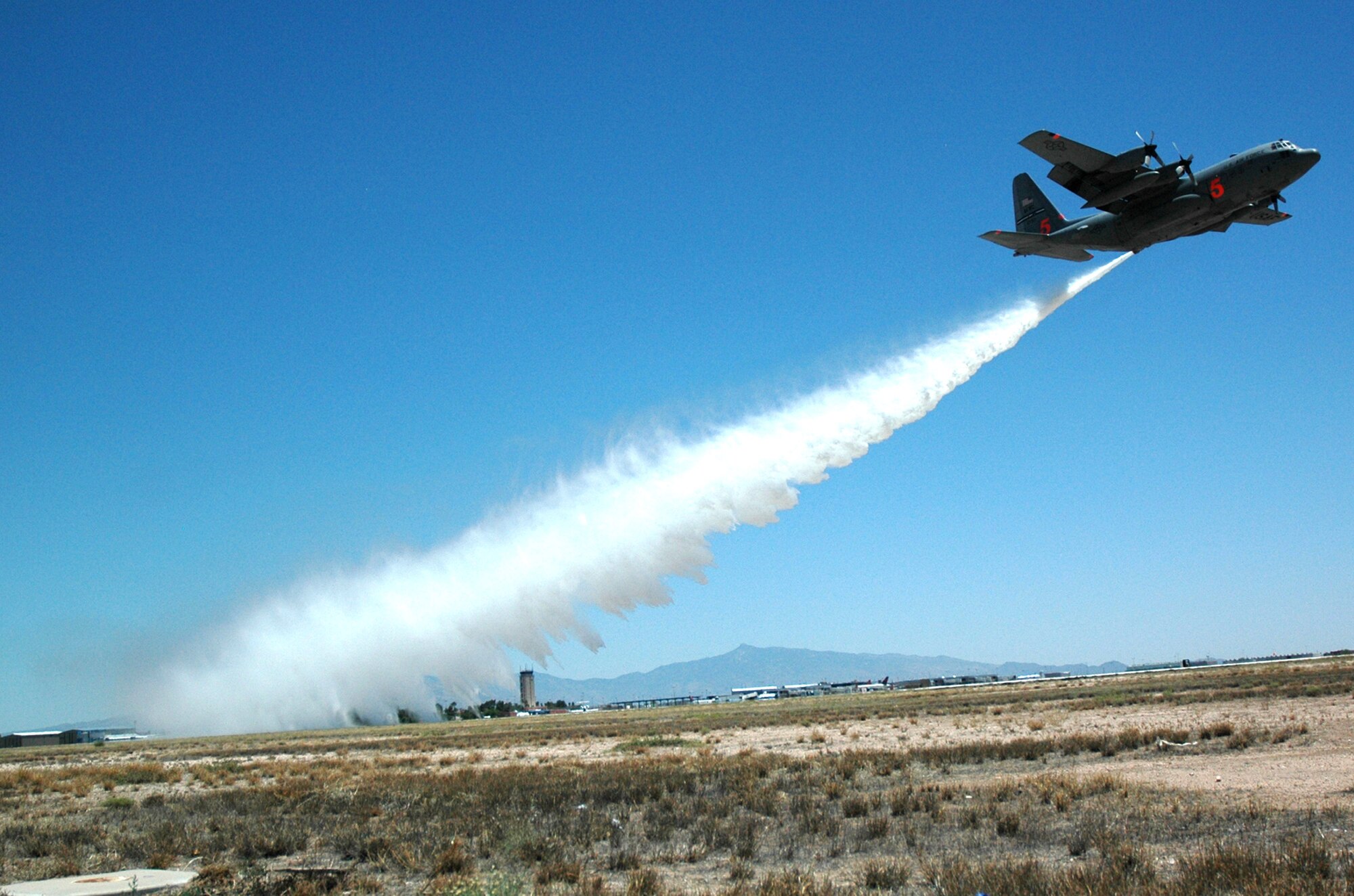 A C-130 Hercules with the Air Force Reserve's 302nd Airlift Wing from Peterson Air Force Base, Colo., drops a load of water from the plane's Military Airborne Firefighting System May 6 at the Tucson International Airport in Arizona. (U.S. Air Force photo/Capt. Jody Ritchie) 

