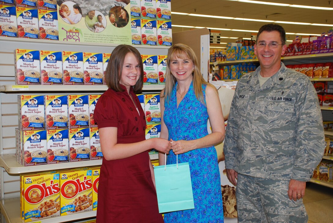 Winner of Quaker Oat's National Military Mom Essay Contest Katie Rice, 12, presents her mom Debbie with a 500 dollar gift certificate to Tiffany's & Co. for Mother's Day May 7. Katie received the gift certificate as the grand prize in the essay contest. Also pictured is Lt. Col. Craig Rice, Katie's father. (U.S. Air Force photo/Airman 1st Class Candy Miller)