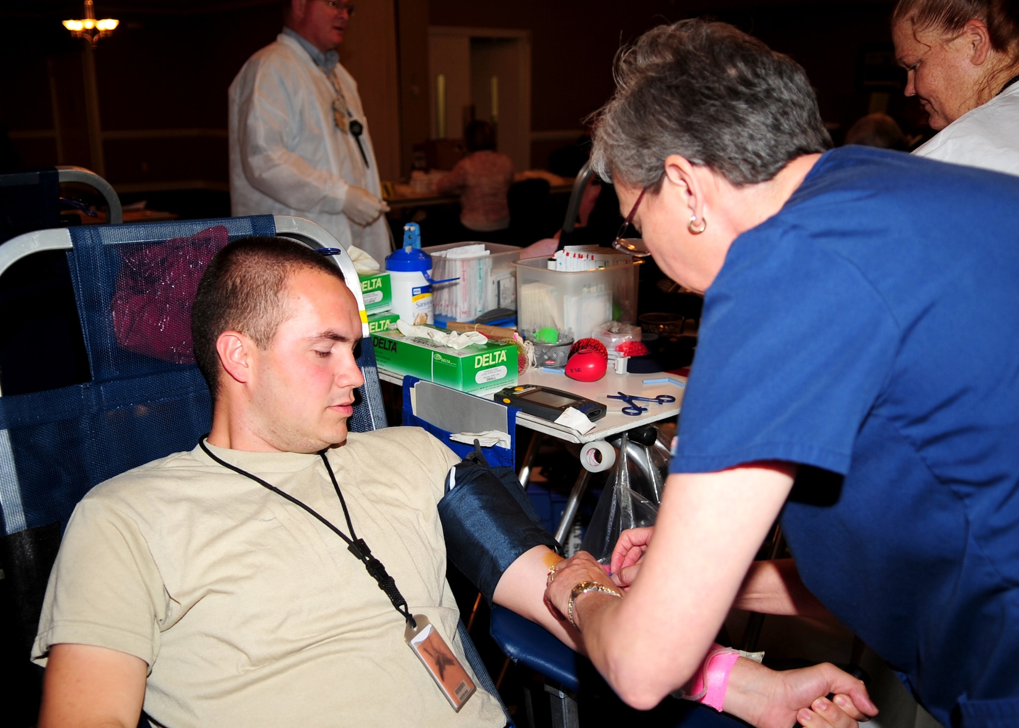 Senior Airman Johnny Farmer, 4th Aircraft Maintenance Squadron, watches as Harriet Pegram prepares to draw blood for the Red Cross blood drive at Seymour Johnson Air Force Base, N.C., May 7, 2009. Only 3 to 5 percent of civilians in America eligible to donate blood participate compared to 20 percent of service members. (U.S. Air Force photo by Airman 1st Class Rae Perry)