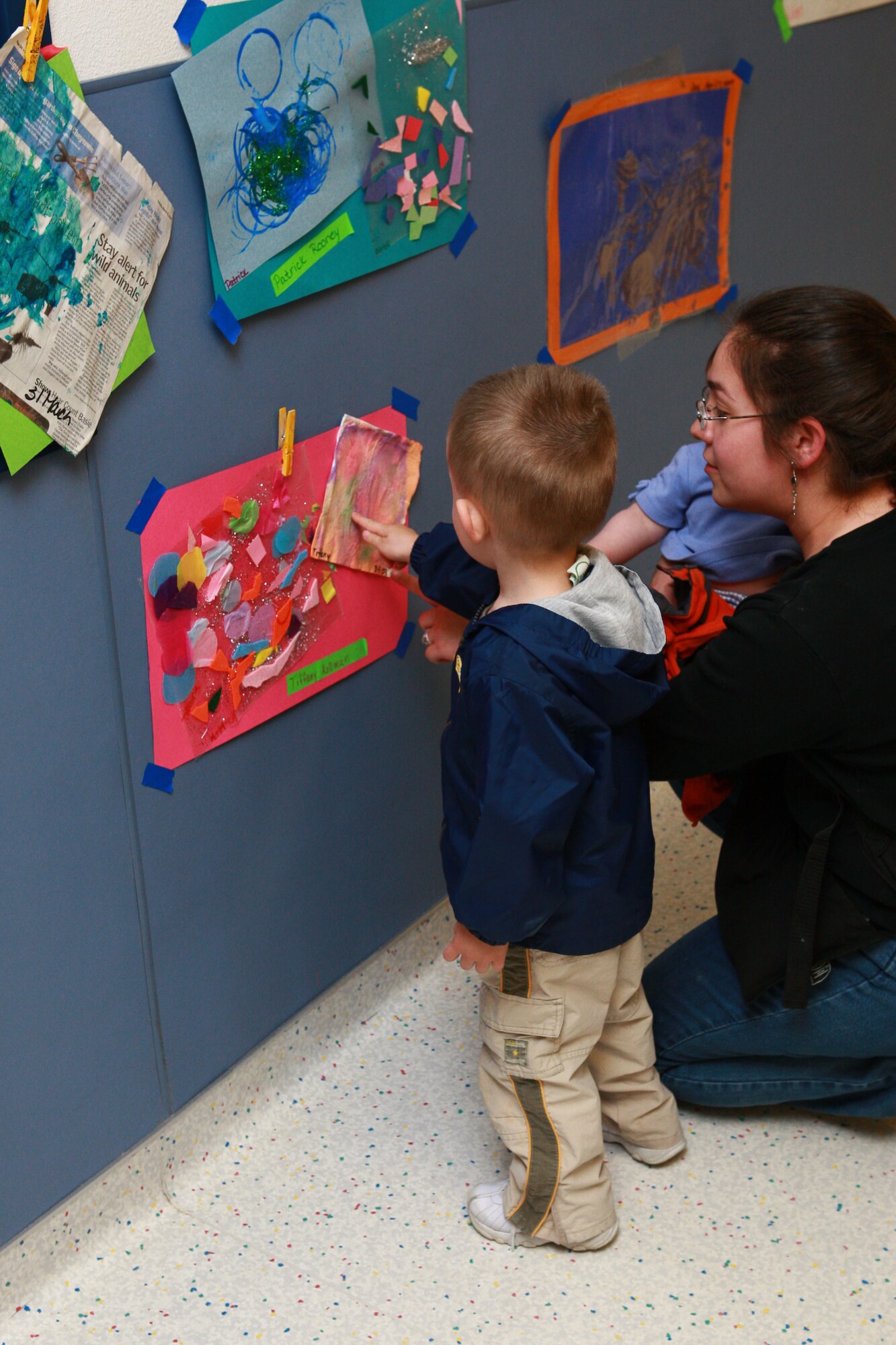 Gary Smith and his mother, Maribel, view the different pieces of art taped to the walls of the CDC for the second annual spring art show. The children prepared for almost a month to put on the show. (Photo by Jeff Allred)