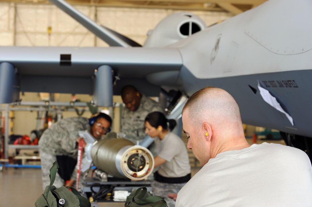 Senior Airman Jason Atwell operates a bomb lift while Staff Sgt. Stephanie Hughes and Senior Airman Gale Passe prepare to load a AGM-114 Hellfire II air-to-ground missile onto the MQ-9 Reaper during weapons load training April 22 at Creech Air Force Base, Nev. Reaper load crewmembers were conducting monthly training to maintain their qualifications on the airframe. (U.S. Air Force photo/Senior Airman Nadine Y. Barclay)
