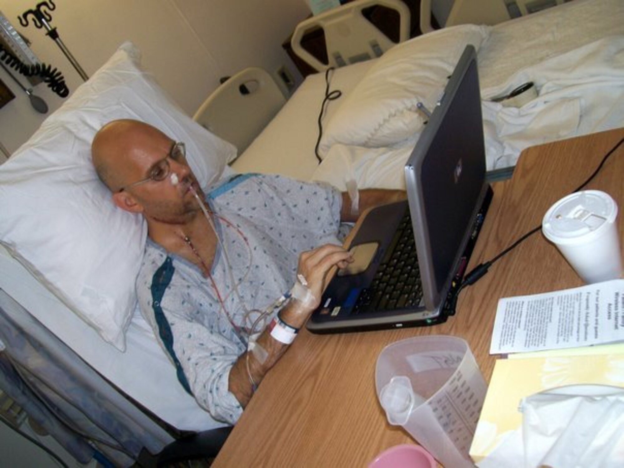 Master Sgt. Mike Sanders writes an online journal entry after undergoing surgery to remove cancer from his neck and throat in 2007.  His son, Shawn, setup the computer for Sergeant Sanders to stay in touch with family and friends who had been following his progress since receiving a cancer diagnosis earlier in the year. (Photo courtesy Master Sgt. Mike Sanders)