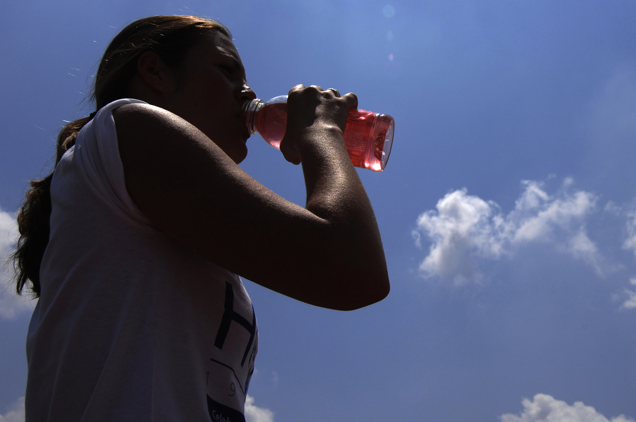 Woman standing outside drinking a sports drink.