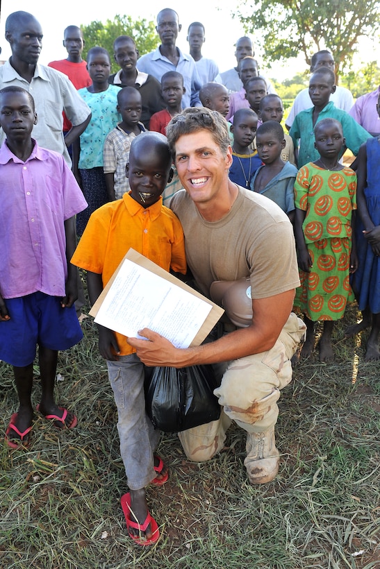 U.S. Navy Petty Officer 2nd Class Peter A. Belcastro poses for a photo with a boy after learning the child had been accepted to a private school as a result of Belcastro's financial sponsorship, Libra, Uganda, May 5, 2009. Belcastro is assigned to Naval Mobile Construction Battalion 11, Combined Joint Task Force-Horn of Africa.