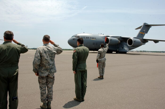 Members of team Charleston salute as Tech. Sgt. Clint Hutchinson ensures the wing tip of a C-17, transporting the Inspector General team, is clear from obstruction on the flightline here May 11. CAFB underwent a week long unit compliance inspection including a base wide exercise to ensure mission readiness capabilities. Sergeant Hutchinson is assigned to the 437th Aircraft Maintenance Squadron. (U.S. Air Force photo/Staff Sgt. Marie Cassetty)