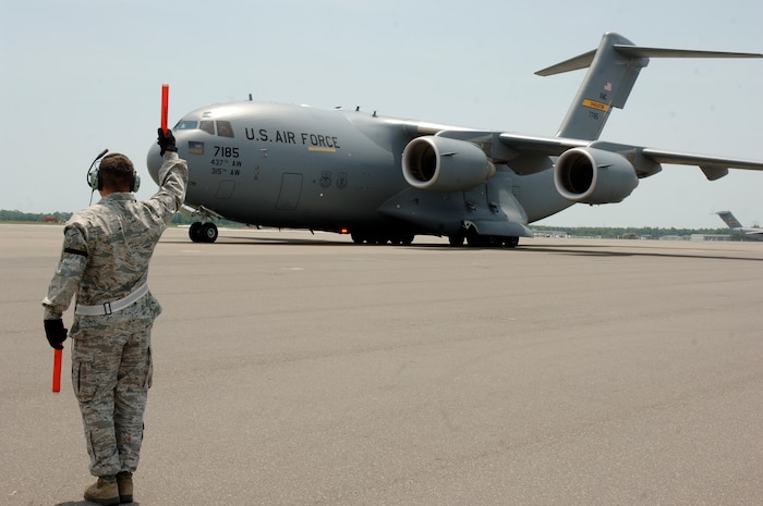 Tech. Sgt. Clint Hutchinson ensures the wing tip of a C-17, transporting the Inspector General team, is clear from obstruction on the flightline here May 11. CAFB underwent a week long unit compliance inspection including a base wide exercise to ensure mission readiness capabilities. Sergeant Hutchinson is assigned to the 437th Aircraft Maintenance Squadron. (U.S. Air Force photo/Staff Sgt. Marie Cassetty)